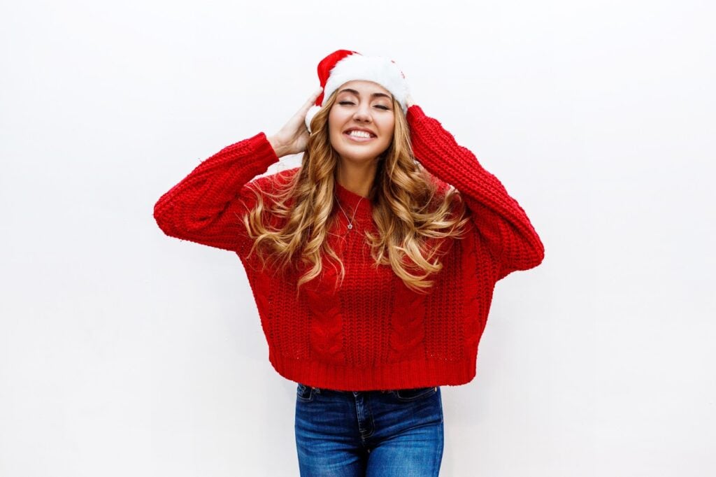 Girl in a red sweater and santa hat posing.