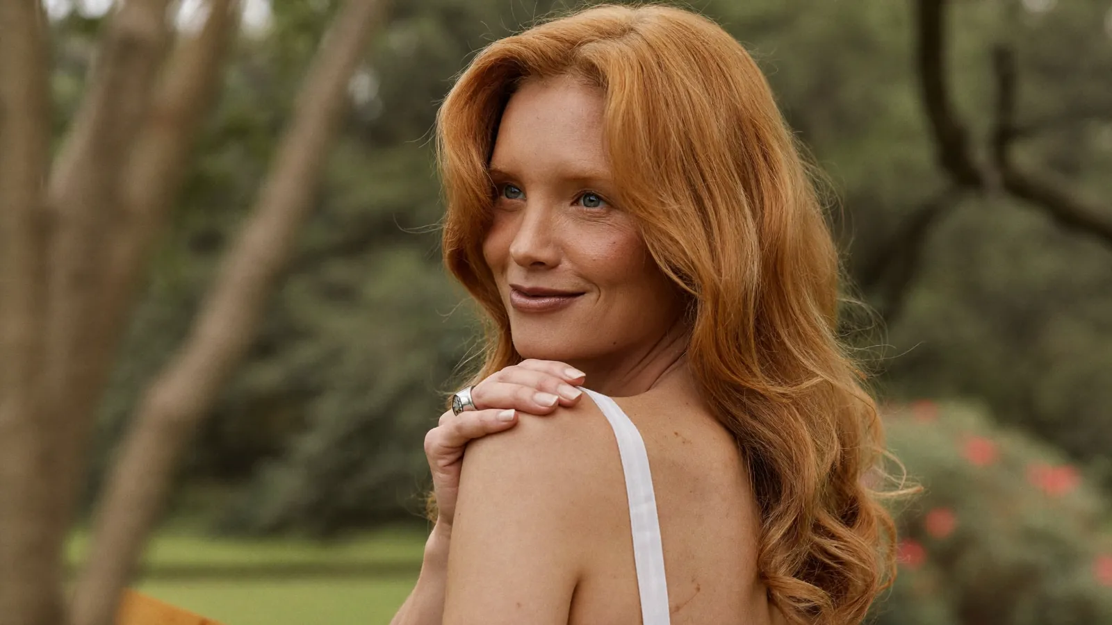Woman with long auburn hair smiling outdoors