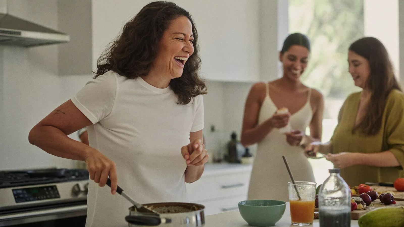 Three women laughing together in a kitchen