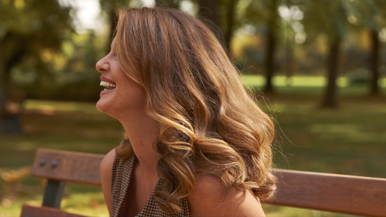 Woman smiling outdoors on a park bench