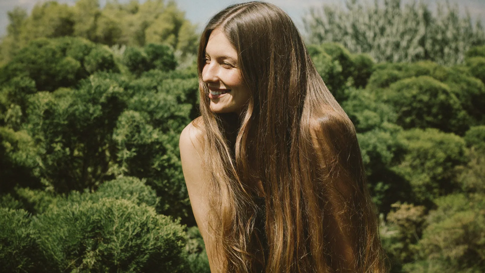 Woman with long hair outdoors among greenery