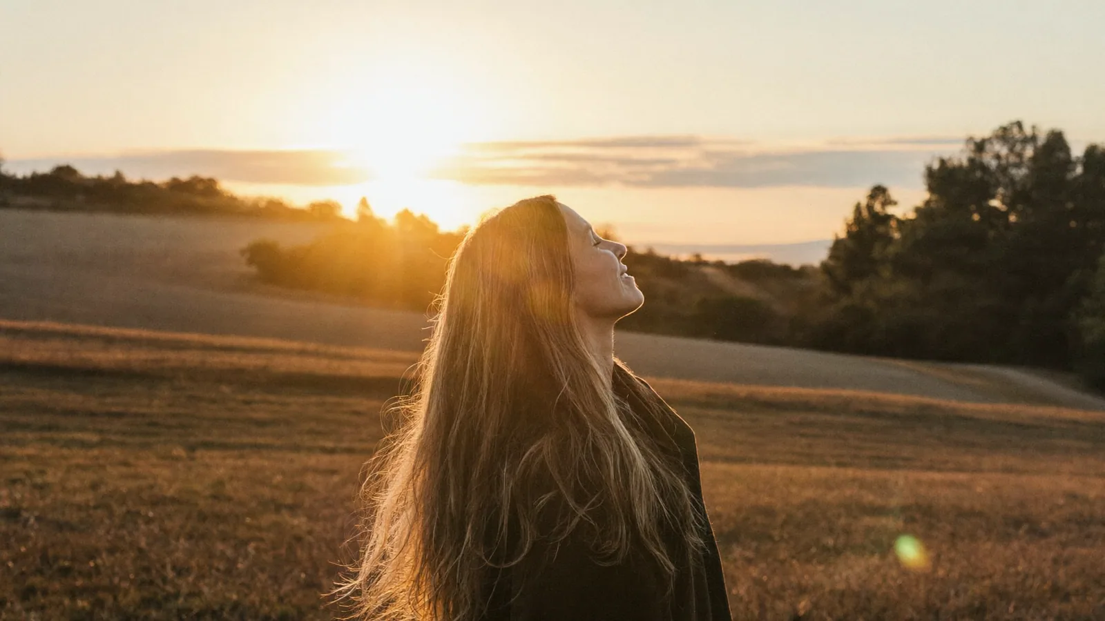Woman standing in a golden field at sunset