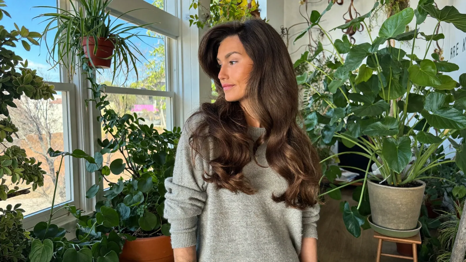 Woman with long wavy hair by a sunny window